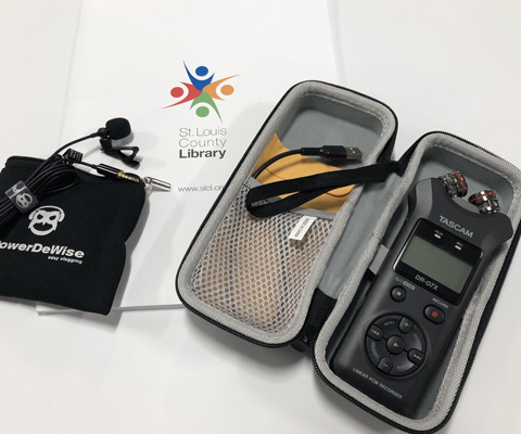 Oral History Kit open case with portable recorder and mic sitting on top of printed instruction booklet with SLCL logo on it