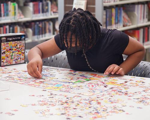 African American teen wearing a mask doing a puzzle at the library
