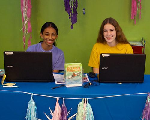 Two teens volunteering at the library during Summer Reading Club